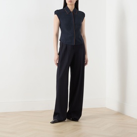 Model wearing Max Mara Studio Midnight Blue silk sleeveless zip-front shirt with wide-leg black trousers and black heeled mules.