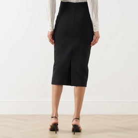 Model wearing Max Mara Studio black midi pencil skirt with back vent, styled with a white blouse and black heeled mules.