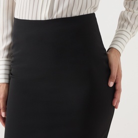 Model wearing Max Mara Studio black pencil skirt in stretch fabric, styled with a white pinstripe shirt. Close-up detail view.