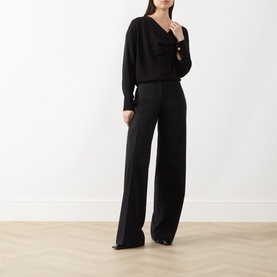 Model wearing Max Mara Studio black triacetate blend top with V-neck and long sleeves, styled with wide-leg black trousers.