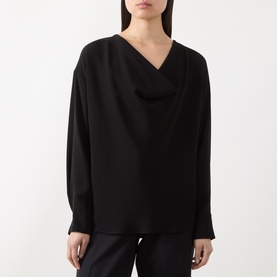 Model wearing Max Mara Studio black long-sleeve top with draped V-neckline, styled with black trousers.