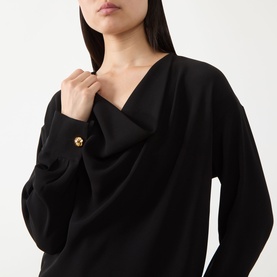 Model wearing Max Mara Studio black V-neck top with draped neckline and gold floral button cuff detail, long sleeves