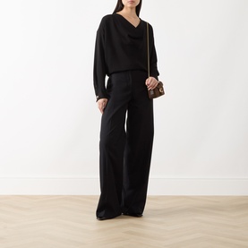 Model wearing Max Mara Studio black triacetate blend top with wide-leg trousers, styled with a small chain-strap shoulder bag.