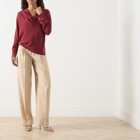 Model wearing Max Mara Studio ruby draped-neck top with wide-leg sand trousers and nude mule heels.