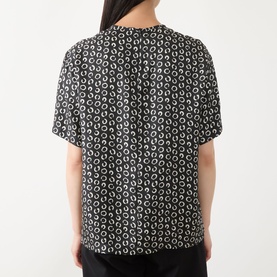 Model wearing Max Mara Studio Mambo Printed Blouse in black and white allover print, short sleeves, round neckline, back view