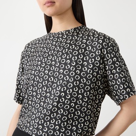 Model wearing Max Mara Studio Mambo Printed Blouse in black and white allover circle print, round neckline, short sleeves