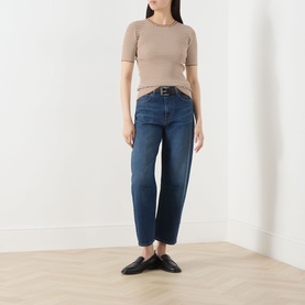 Model wearing Max Mara Studio Caramel White short-sleeve ribbed top, styled with dark blue cropped jeans and black flat mules.