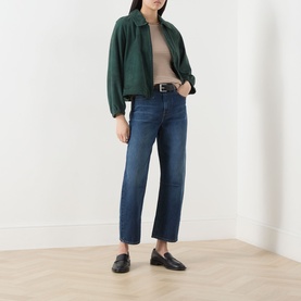 Model wearing Max Mara Studio Caramel White top, styled with dark green bomber jacket, blue cropped jeans and black loafers.