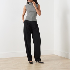 Model wearing Max Mara Studio Black White sleeveless ribbed turtleneck top with black wide-leg trousers and heels.