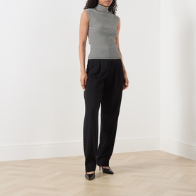 Model wearing Max Mara Studio black white sleeveless ribbed turtleneck top, styled with black wide-leg trousers and black heels.