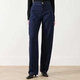 Model wearing dark navy wide-leg straight jeans with high waist and gold-tone button, styled with black heeled boots and black top.