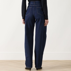 Model wearing dark navy wide-leg high-waist jeans, rear view, styled with a black long-sleeve top and black shoes