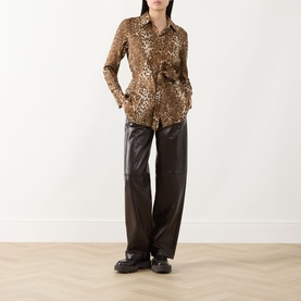 Model wearing Max Mara Studio brown wide-leg faux leather trousers, styled with a leopard print shirt and black chunky loafers.
