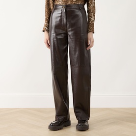 Model wearing Max Mara Studio brown wide-leg faux leather trousers, styled with a leopard-print top and black chunky-sole loafers.
