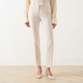 Model wearing Max Mara Studio Natural tailored trousers with slim leg, styled with cream blouse and ivory heeled mules.