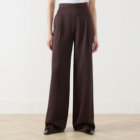Model wearing Max Mara Studio chocolate wide-leg trousers with high waist and front pleats, styled with black shoes