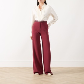 Model wearing Max Mara Studio Ruby wide-leg trousers, styled with a cream blouse and brown belt.