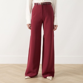 Model wearing Max Mara Studio Ruby wide-leg trousers with slim belt, styled with a white blouse and white heels