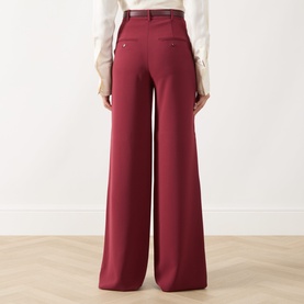 Model wearing Max Mara Studio ruby wide-leg trousers, rear view, styled with a white blouse and brown belt.