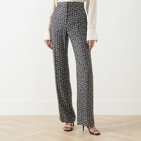 Model wearing Max Mara Studio black and white geometric print silk wide-leg trousers, styled with a white blouse and black strappy heels.