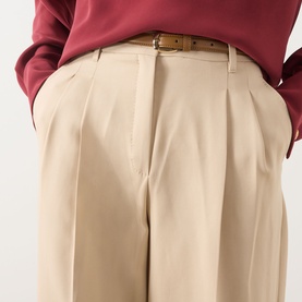 Model wearing Max Mara Studio Adunco Wide Leg Trousers in beige with pleated detailing and tan belt, styled with a burgundy top.