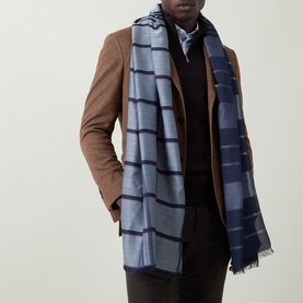 Model with Salvatore Ferragamo Navy Check Cashmere-Silk Scarf with frayed ends, styled over a brown overcoat and dark knitwear.