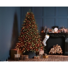 Festive Productions Firefly Lights 1500 LED in multi, red and antique gold tones adorning a decorated Christmas tree beside a fireplace with stocking