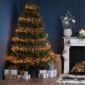 Festive Productions Multifunction Cluster 3000 LED warm white lights decorating a large indoor Christmas tree with wrapped gifts beneath
