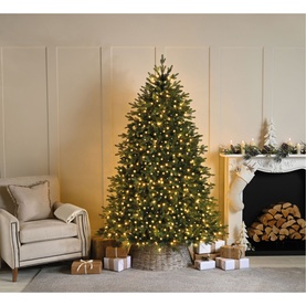 Festive Productions Compact Lights 500 LED warm white lights decorating a full green Christmas tree in a cosy living room with fireplace and wrapped