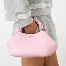 Model carrying Ganni Pink Nectar crossbody bag with knotted top handle, silver hardware detail, styled with grey loungewear set