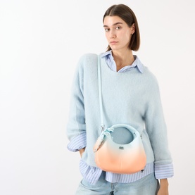 Model carrying Ganni Hobo Mini Crossbody Bag in Country Air, blue-to-peach gradient with silver-tone butterfly hardware, worn crossbody styled with