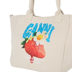 Ganni Sunlight tote bag, cream canvas with strawberry and daisy graphic print, blue logo lettering, twin handles