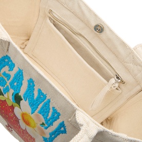 Ganni Sunlight tote bag interior showing cream canvas lining, zip pocket, and open slip pocket with floral strawberry logo detail visible