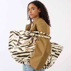 Model carrying Ganni Zebra Logo XXL Shopper Tote Bag in Egret zebra print canvas with carry handles and embroidered logo, styled with khaki jacket