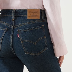 Model wearing Levi's flare jeans in High Vibration dark indigo wash, close-up of back pockets with signature red tab and leather patch.
