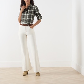 Model wearing Levis cream flare jeans with green plaid shirt and tan heeled mules