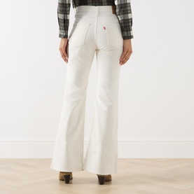 Model wearing Levi's cream flare jeans, back view, paired with a plaid shirt and brown heeled boots.