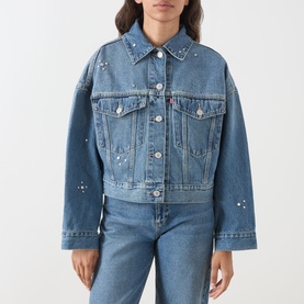 Model wearing Levi's Trip On Drip Trucker denim jacket in mid blue with floral embroidery detail, styled with matching blue denim jeans.