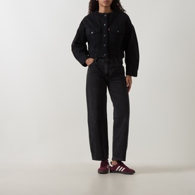 Model wearing Levis Cropped Sherpa Trucker Jacket in Slight Night black, styled with matching black jeans and burgundy trainers.