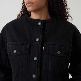Model wearing Levis Cropped Sherpa Trucker Jacket in Slight Night black, showing collarless neckline, sherpa lining detail and front button fastening