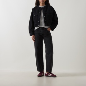 Model wearing Levis Cropped Sherpa Trucker Jacket in Slight Night, black denim, collarless with button front, styled with dark jeans and burgundy