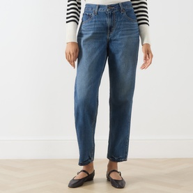 Model wearing Levi's jeans in Let's Fly mid-blue wash, straight leg, styled with a striped top and black Mary Jane flats.