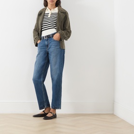 Model wearing Levi's jeans in Let's Fly mid-blue wash, styled with an olive jacket, striped top and black flat shoes.