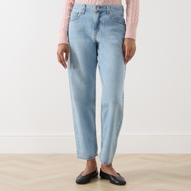 Model wearing Levis Loose Tapered Jeans in Message Sent light wash denim, mid-rise, tapered leg, styled with a pink knit top and black flats.