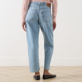 Model wearing Levis Loose Tapered Jeans in Message Sent light wash, back view, styled with a pink cable-knit jumper and black flats.