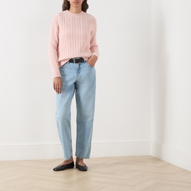 Model wearing Levis Loose Tapered Jeans in light wash denim, mid-rise, tapered leg, styled with a pink cable-knit jumper and black flats.