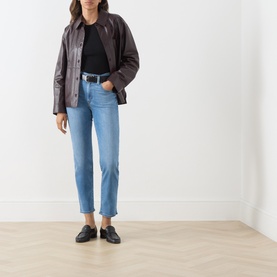Model wearing Levi's True Blue Mid slim jeans with dark leather jacket, black top, belt and loafers.