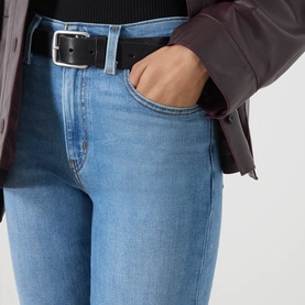 Model wearing Levi's True Blue Mid slim jeans with hand in pocket, styled with dark jacket and black belt.