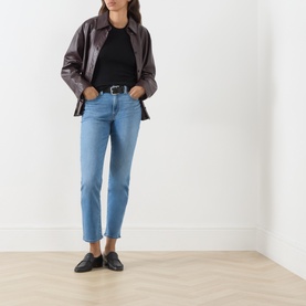 Model wearing Levi's True Blue Mid slim jeans with black tee, dark leather jacket, and black loafers