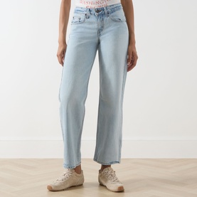 Model wearing Levi's straight jeans in light blue denim, cropped length with raw hem, paired with beige trainers